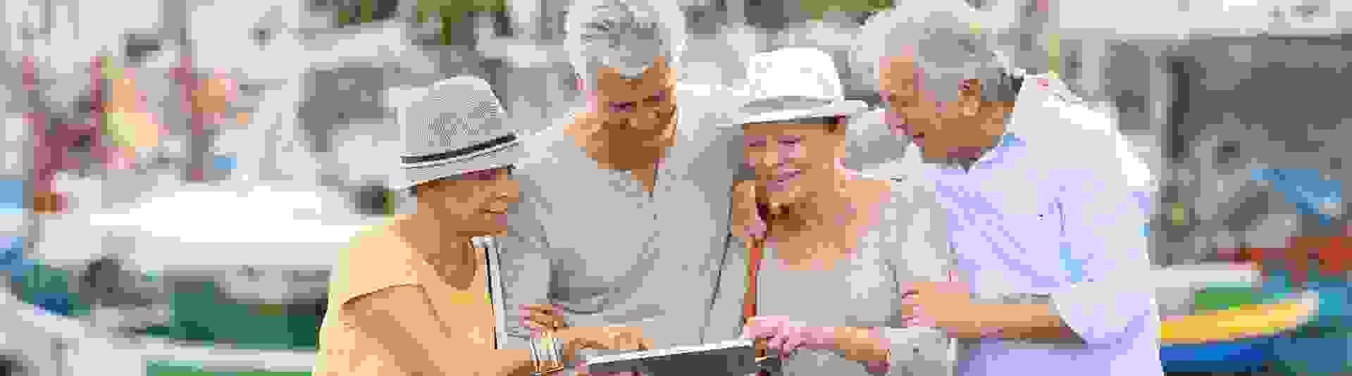 Zwei Männer und zwei Frauen, Arm in Arm, gucken sich etwas auf einem Tablet an