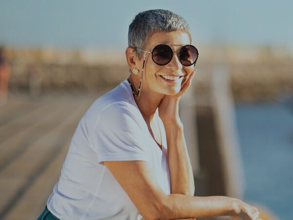 Lächelnde Frau mit Sonnenbrille am Steg mit Booten
