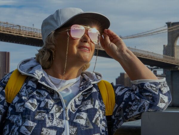 Frau mit Kappe und Sonnenbrille an der Brooklyn Bridge in New York